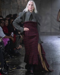 a woman with white hair walks down the runway
